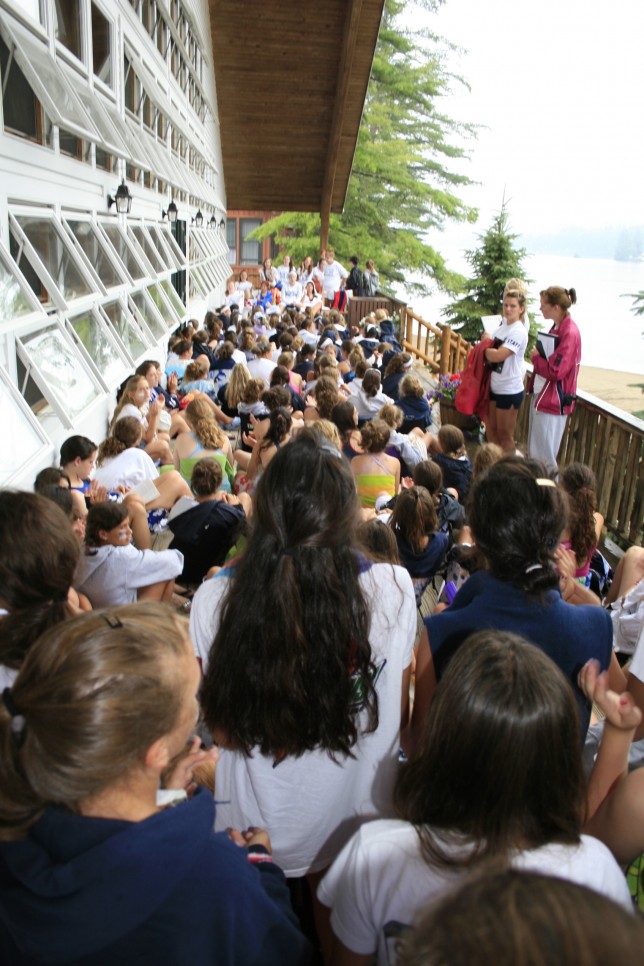 Campers listen to announcements on the front porch of the dining hall