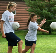 Two girls practicing their volleyball serves