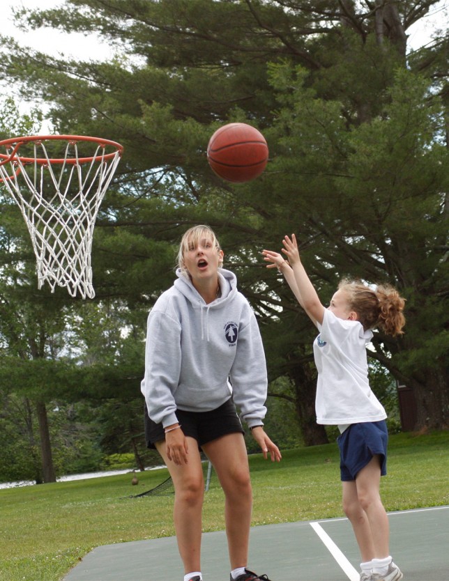 A basketball coach helps a young, aspiring player