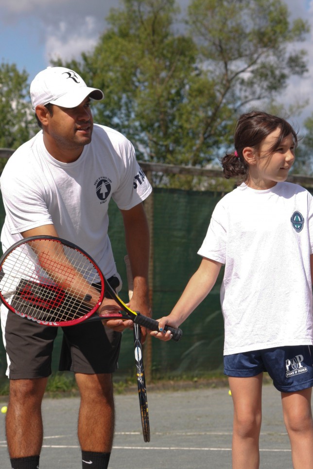 20090713138 Lead tennis instructor helping a camper with her swing