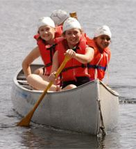 Campers rowing towards the camera in a canoe