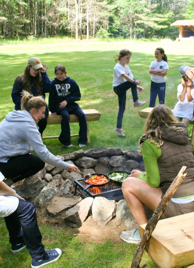201006309937 Counselors preparing breakfast over a fire for sleepy campers