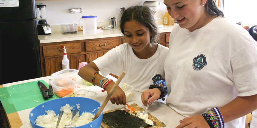 A camper and a counselor making a delicious meal.