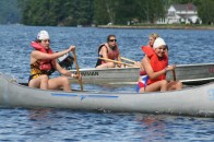 Campers and counselors on the lake in canoe and boat