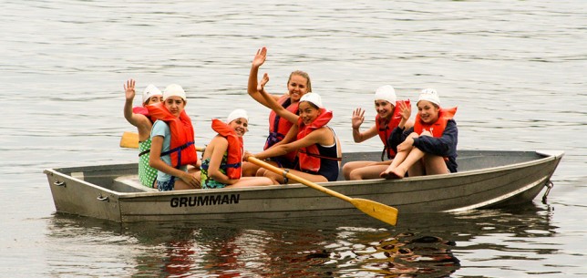 201007201909 A counselor waving from a boat full of campers