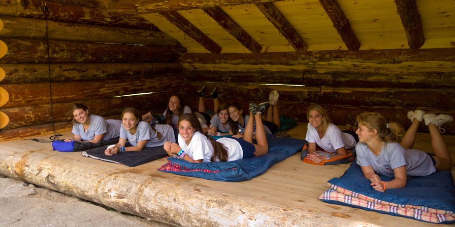 Campers on their sleeping bags in a camping shelter