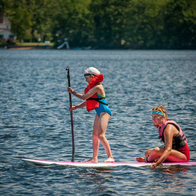 Camper learns stand-up paddle board.