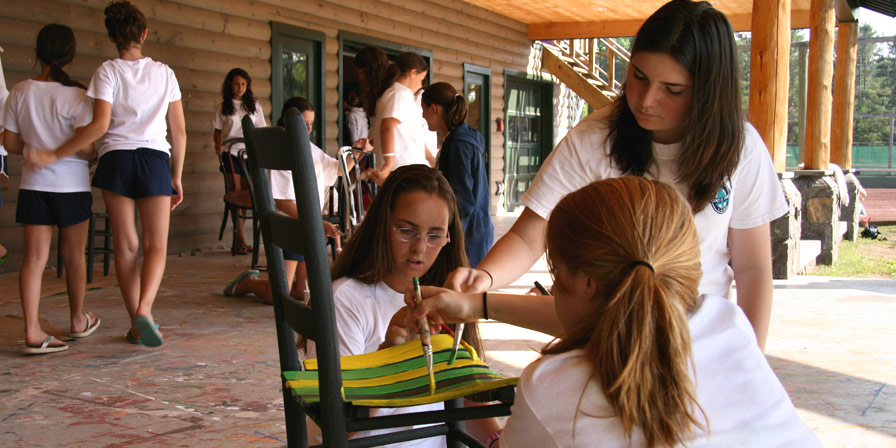 Campers and a counselor painting a chair