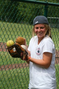 A counselor carrying balls in her softball mit