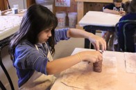 A camper making a pot in the ceramics building